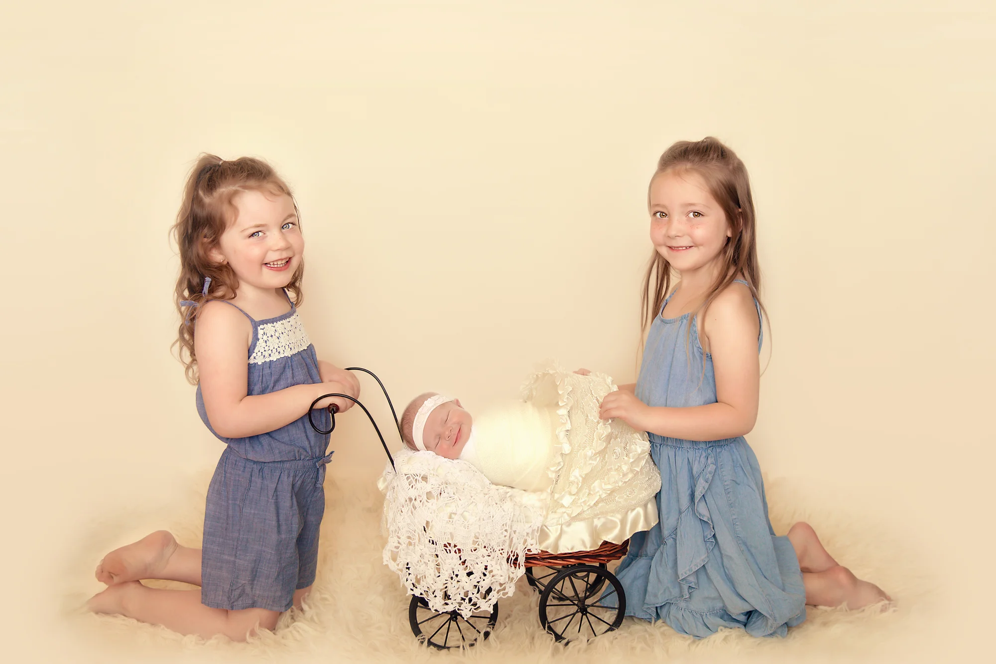 Newborn Photoshoot inspiration ideas. Calgary and Airdrie, Alberta Newborn and Baby photographer - Milashka Photography. Siblings shot - 2 sisters are holding a little pram where their newborn baby sister is sleeping. All 3 sisters are smiling.