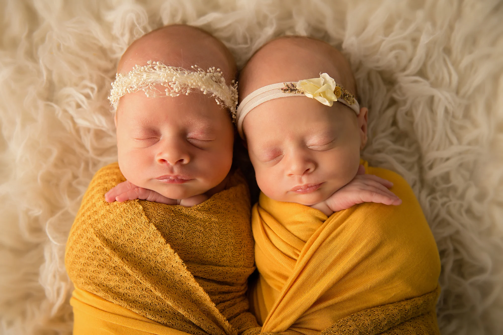 Twins Photography in Calgary, Alberta by Milashka Photography. Twin sisters are lying side by side wrapped in the mustard colour wraps.