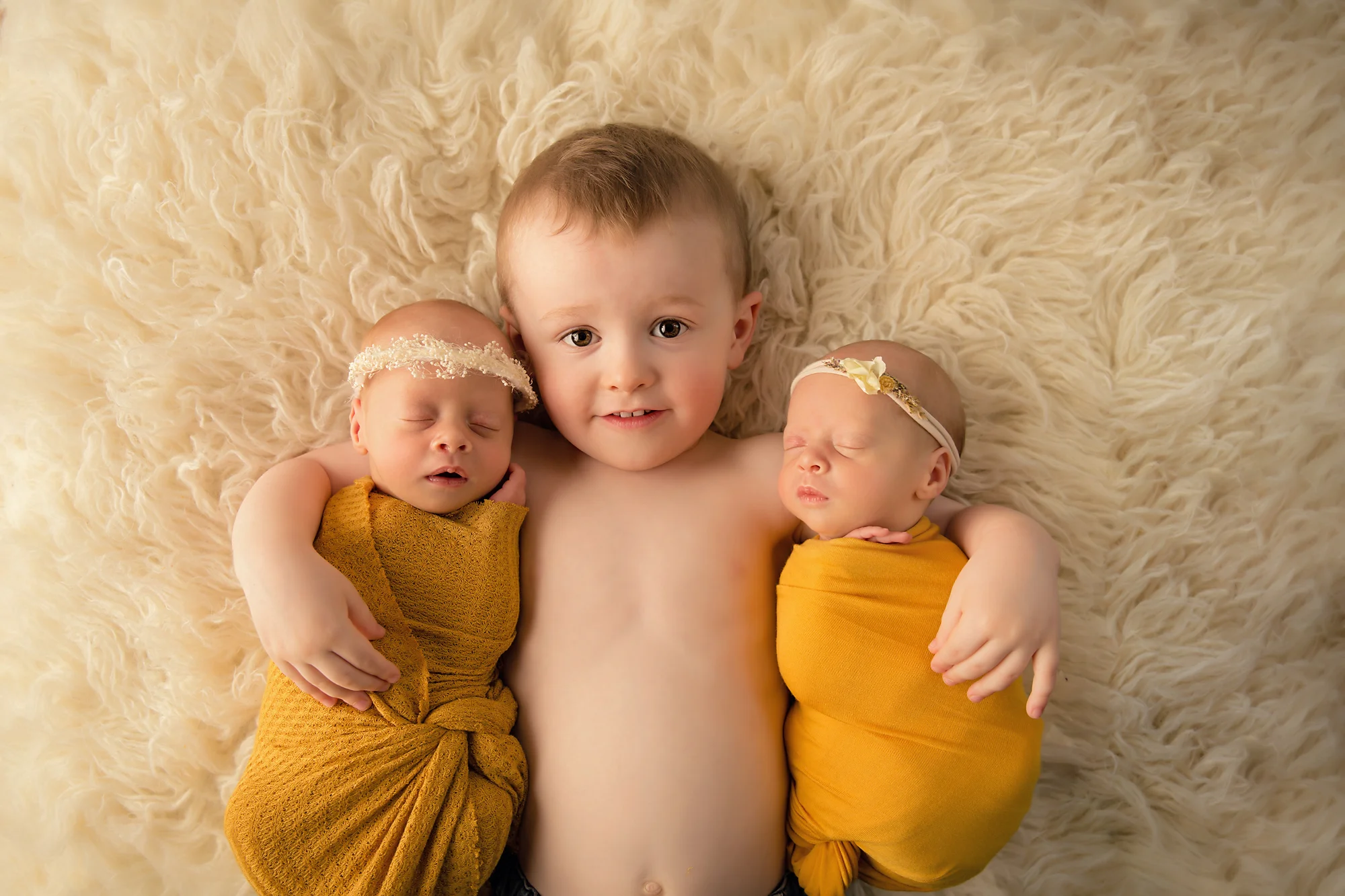Twins Photography in Calgary, Alberta by Milashka Photography. Twin sisters and their big brother posed on a flokati rug