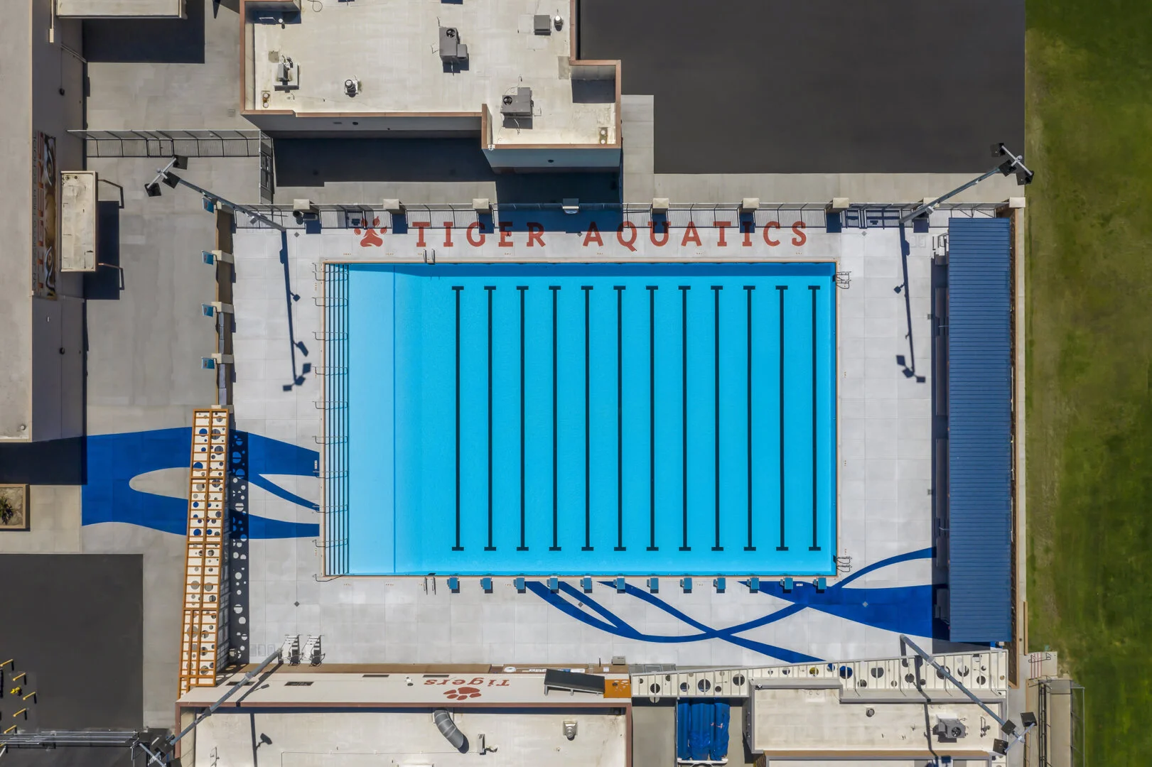 Blue abstract lines wave across the deck and serve as a wayfinding feature, pulling spectators to the bleachers where they can keep cool beneath orange cantilevered shade structures.
