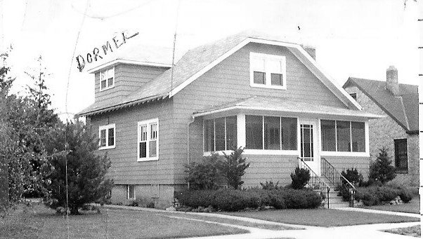 Black-and-white photo of a two-story wood-sided house with an enclosed front porch, front steps, and a small dormer (handwritten label "DORMER").