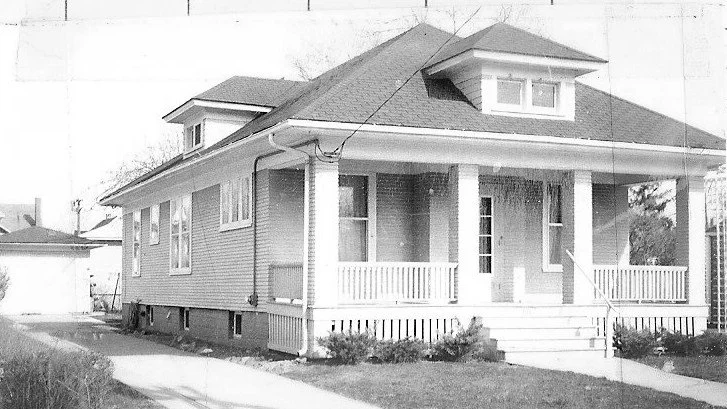 Single-story bungalow with a covered front porch, steps, two dormer windows, driveway and detached garage.