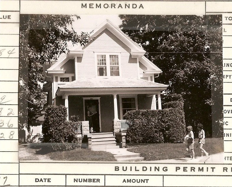 Black-and-white photo of a two-story house with a front porch and hedges; two children walk on the sidewalk; header reads "MEMORANDA" and footer shows "BUILDING PERMIT."