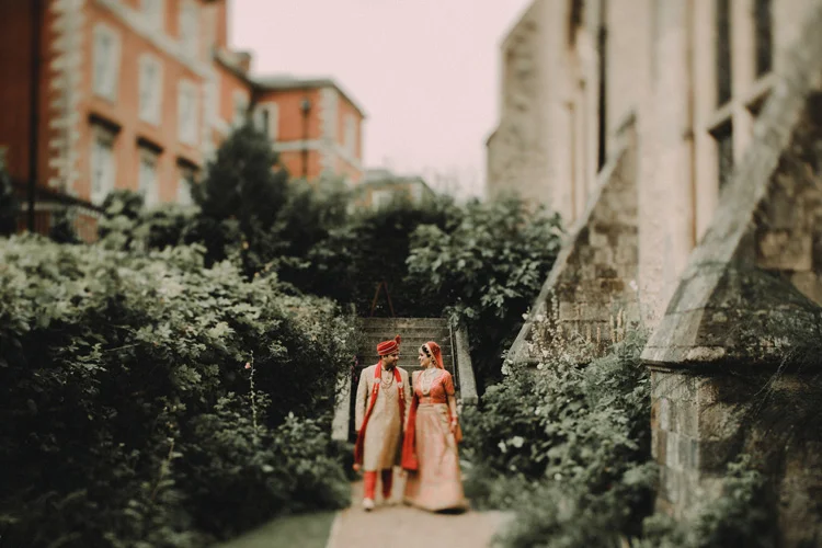 indian couple hold hands in church garden after traditional wedding