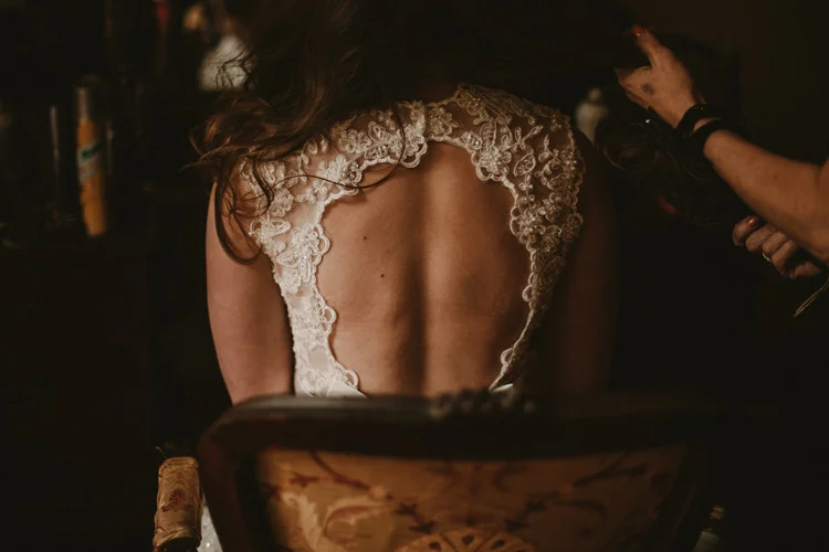 bride in vintage dress gets her hair done during bridal prep