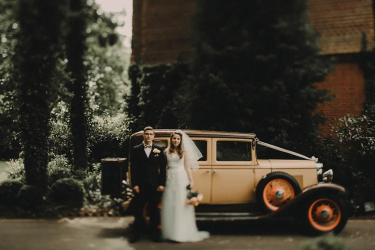 bride and groom stand next to vintage car in surrey wedding
