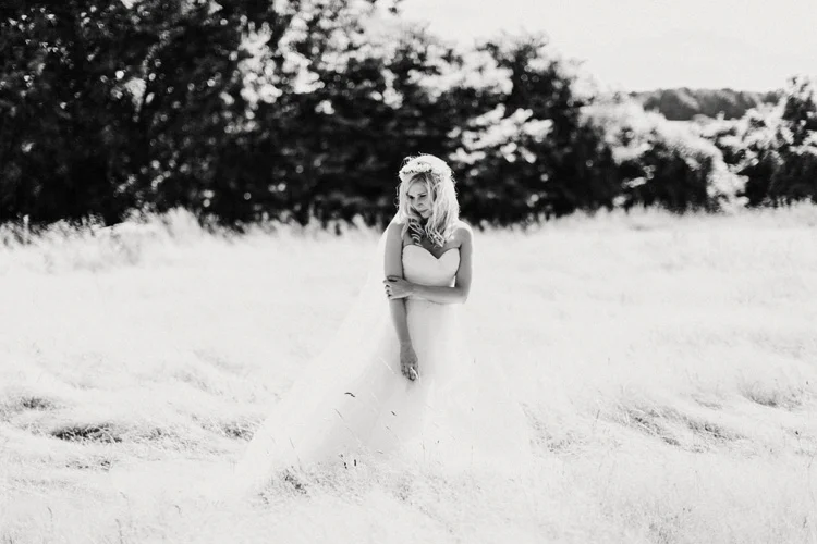 boho bride stands in hay field in chesham wedding