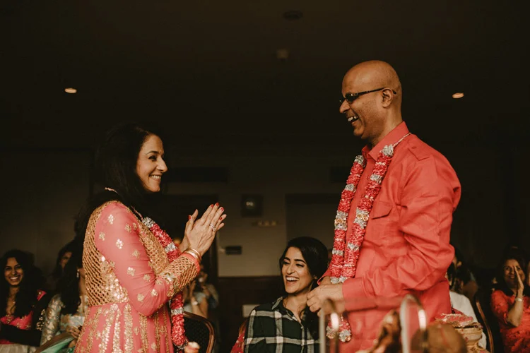 brides mum and dad laugh after finishing ritual in puja