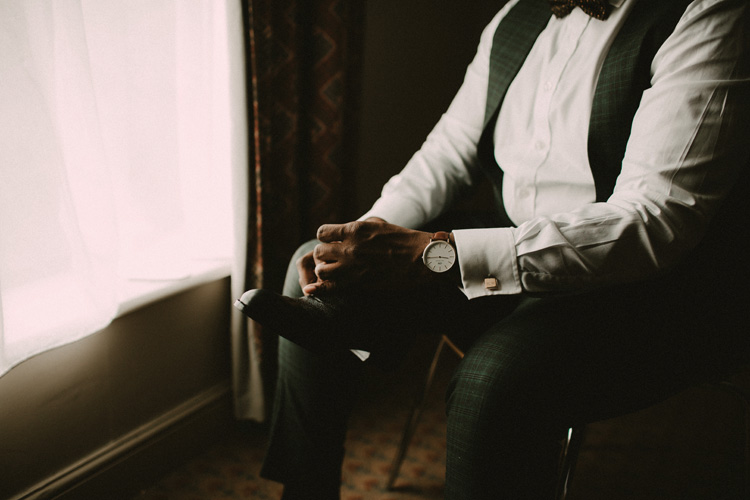 groom puts on shoes in froyle park wedding