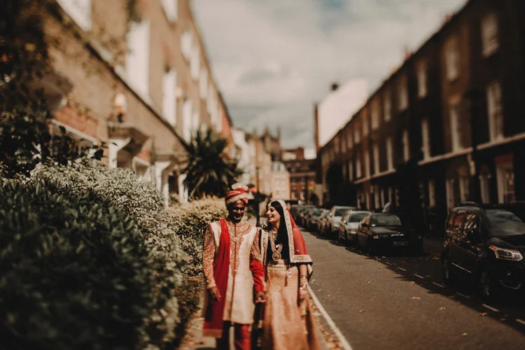 indian bride and groom hold hands walking down london street
