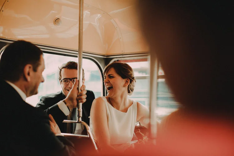 russian bride laughs with guests on red london bus
