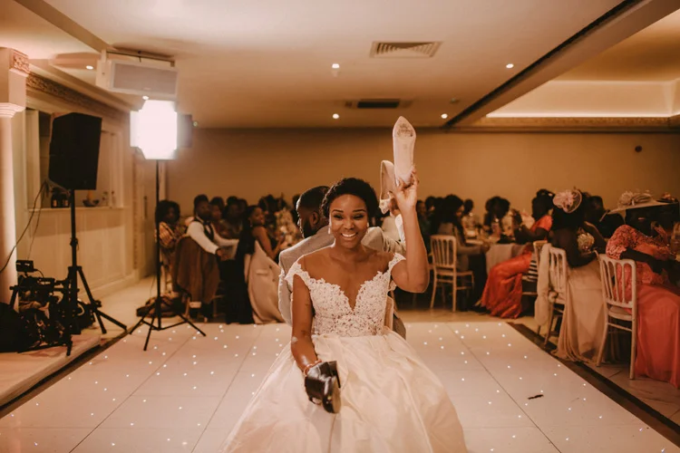 bride holds up shoe in froyle park wedding reception