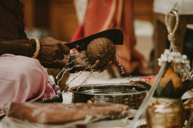 hindu priest opens coconut in traditional hindu ceremony