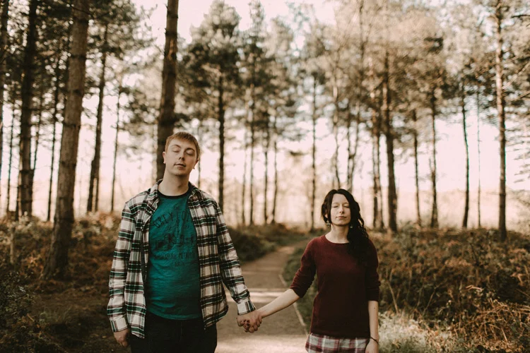 couple hold hands and close eyes in birchington forest engagement session