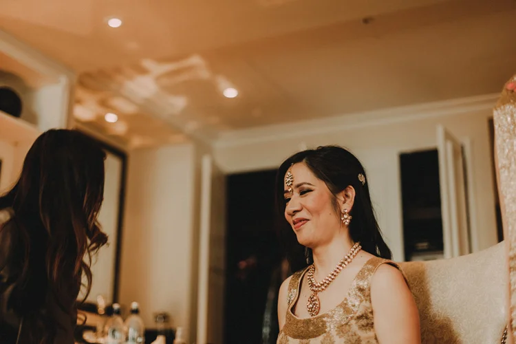 asian bride smiles whilst getting ready for hindu wedding ceremony