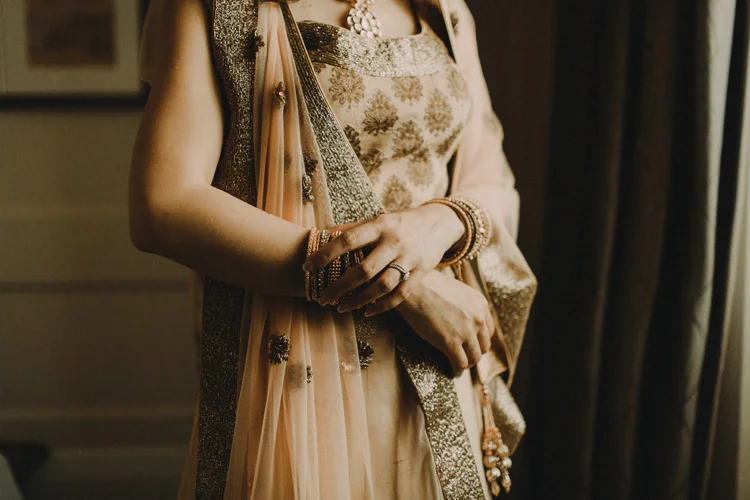 asian bride adjusts bracelet before traditional hindu ceremony