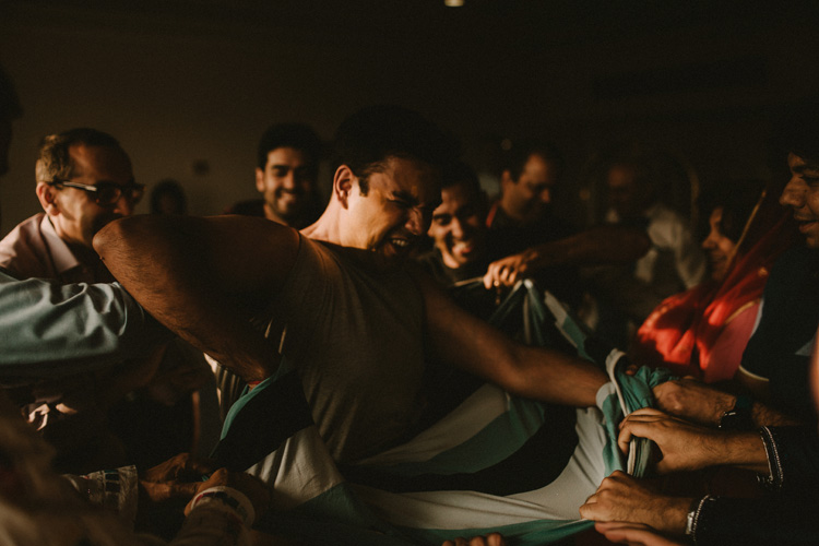 groomsmen tearing grooms clothes during ritual in hindu puja