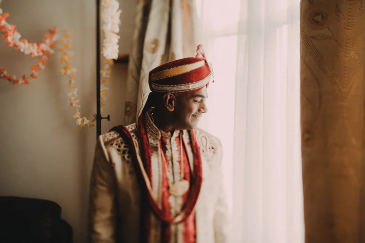 groom looks out window ready for his hindu ceremony