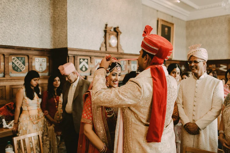 indian groom places flower garland around brides neck in hindu wedding