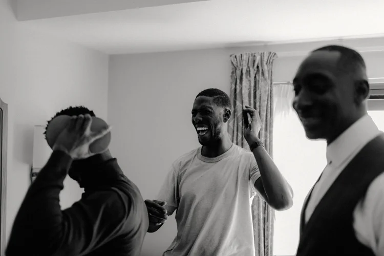 groomsmen share jokes whilst getting ready for froyle park wedding