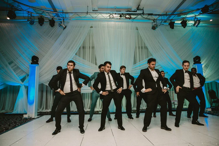 groom and groomsmen dance for bride during hindu wedding reception