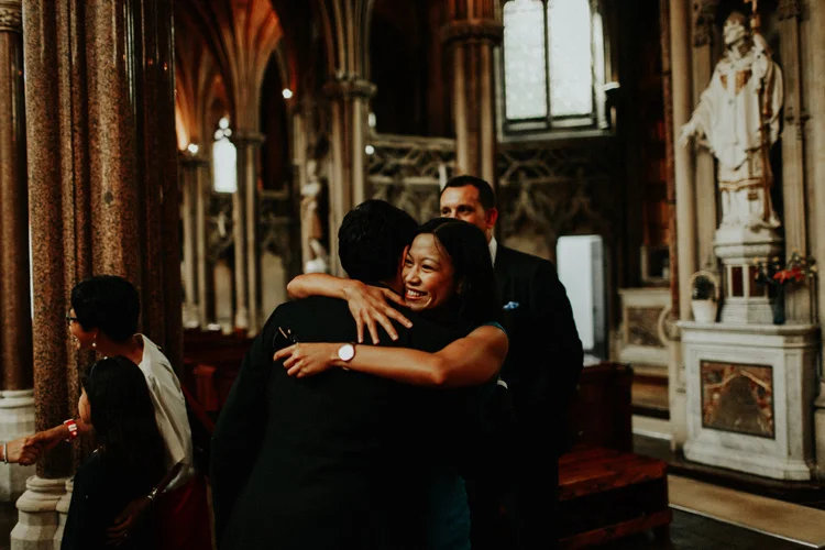 groom hugs family member after farm street church wedding