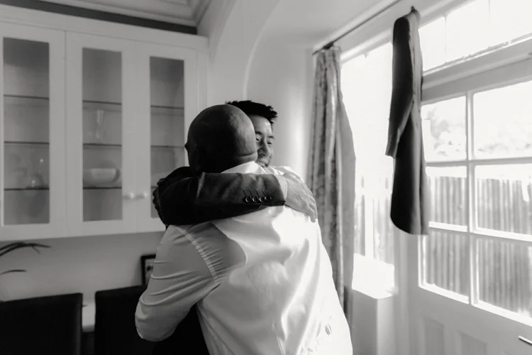 groom and best man embrace whilst getting ready for syon park wedding