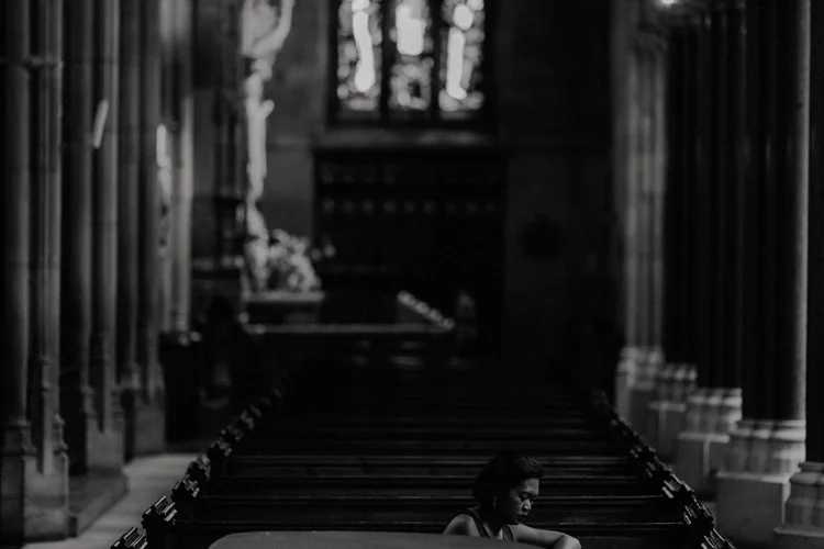 wedding guest sits in pew in farm street church wedding