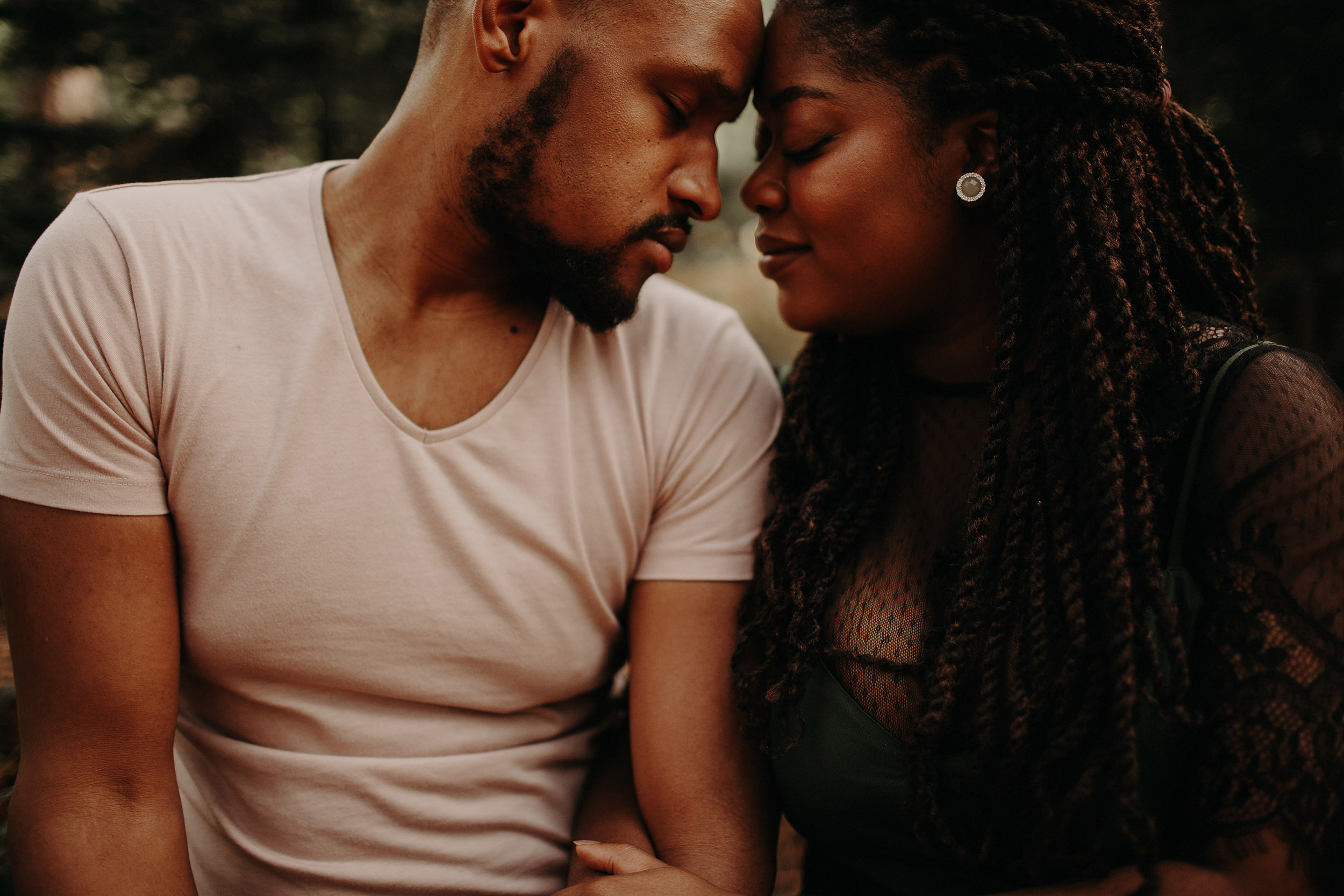 engaged couple touch foreheads whilst in the black park