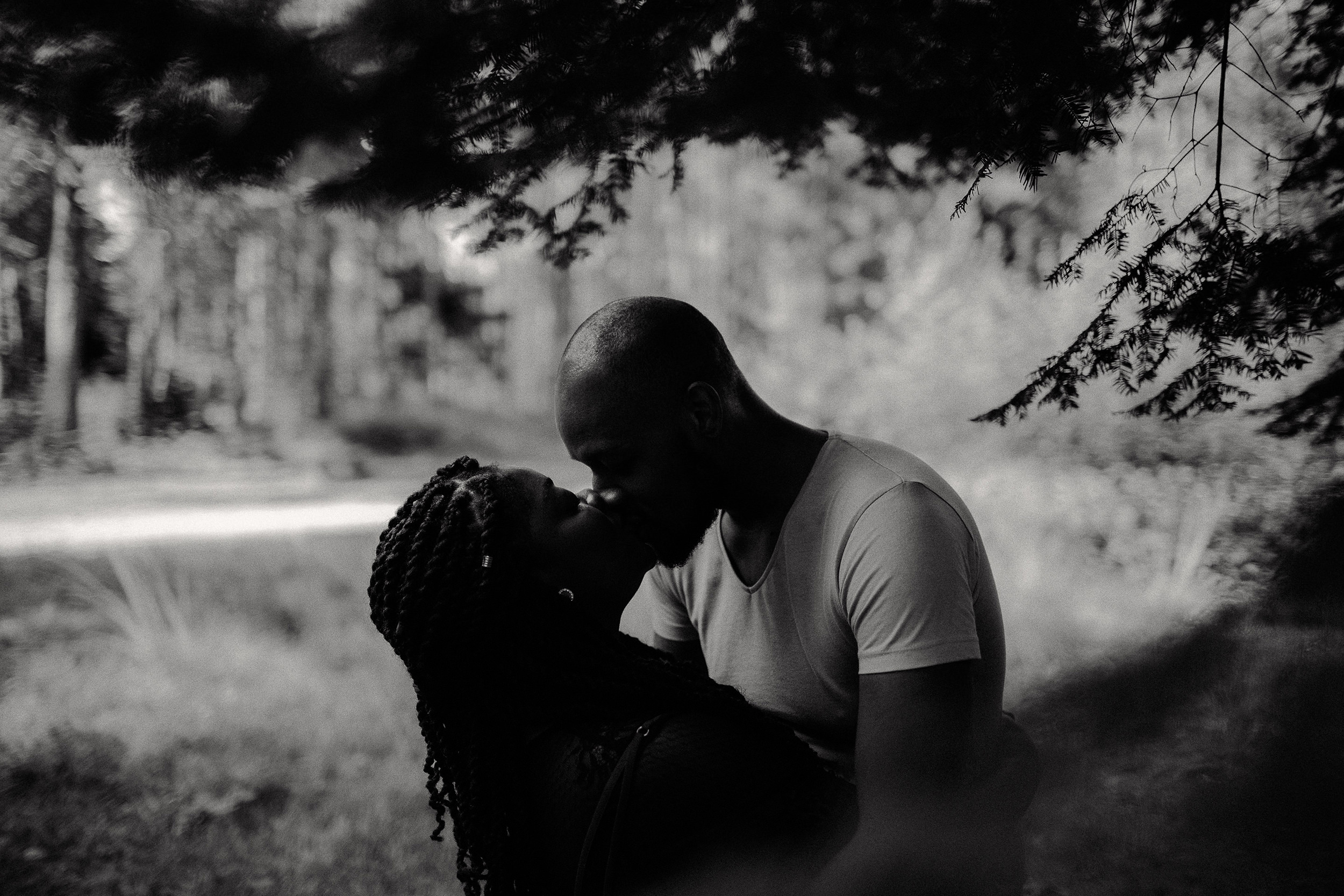 engaged couple share a kiss whilst in the black park