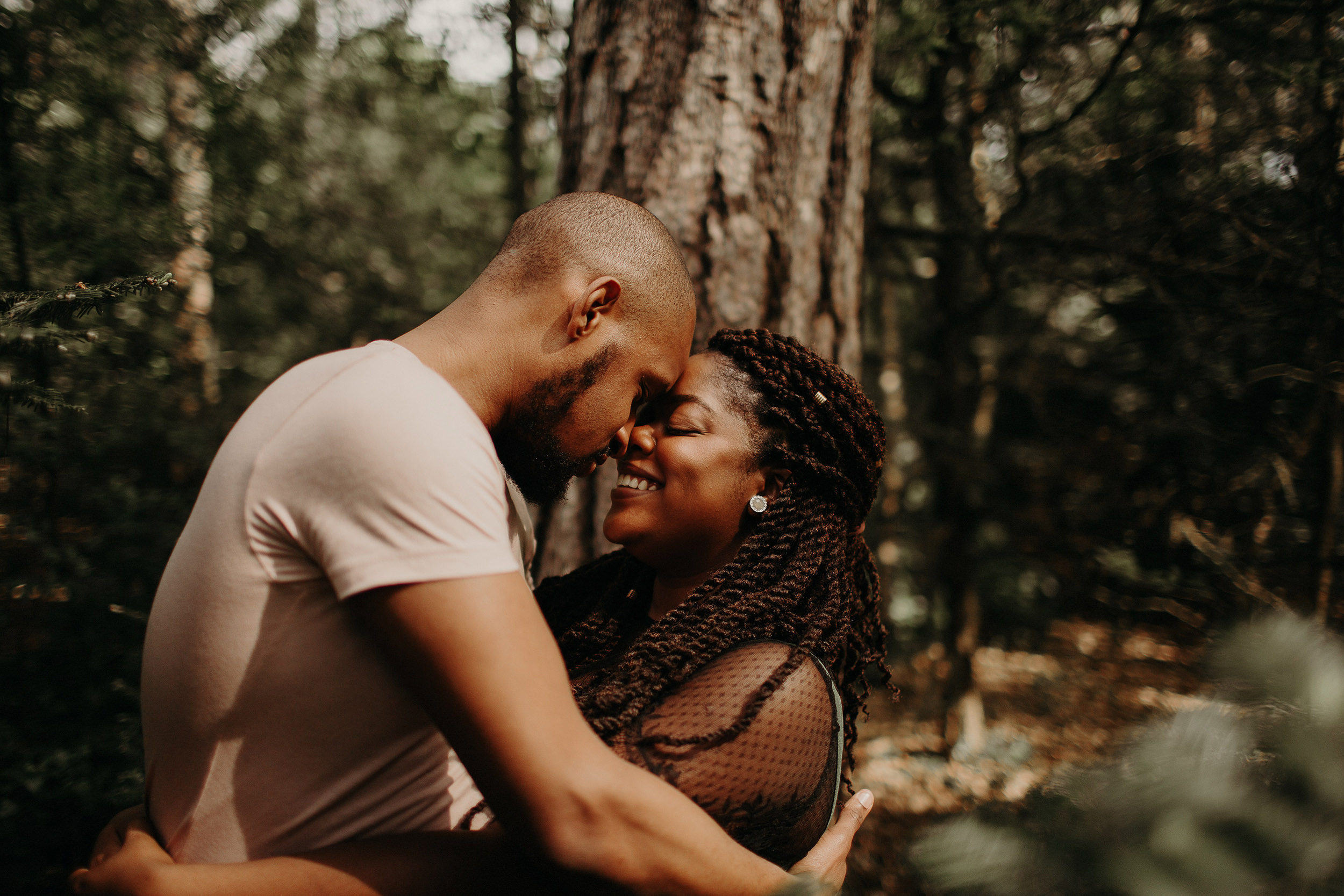 engaged couple touch foreheads whilst in the black park