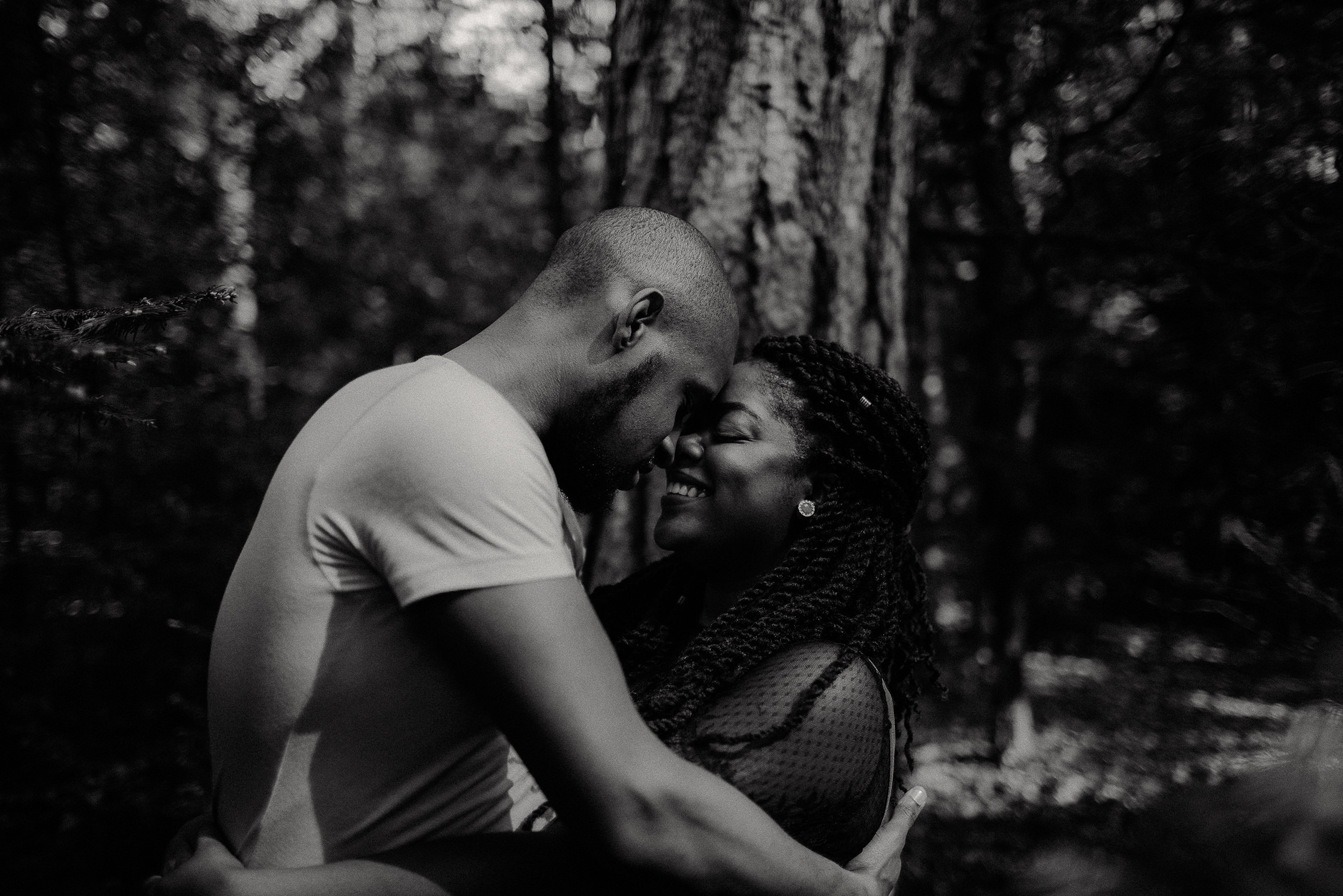 engaged couple touch foreheads whilst in the black park