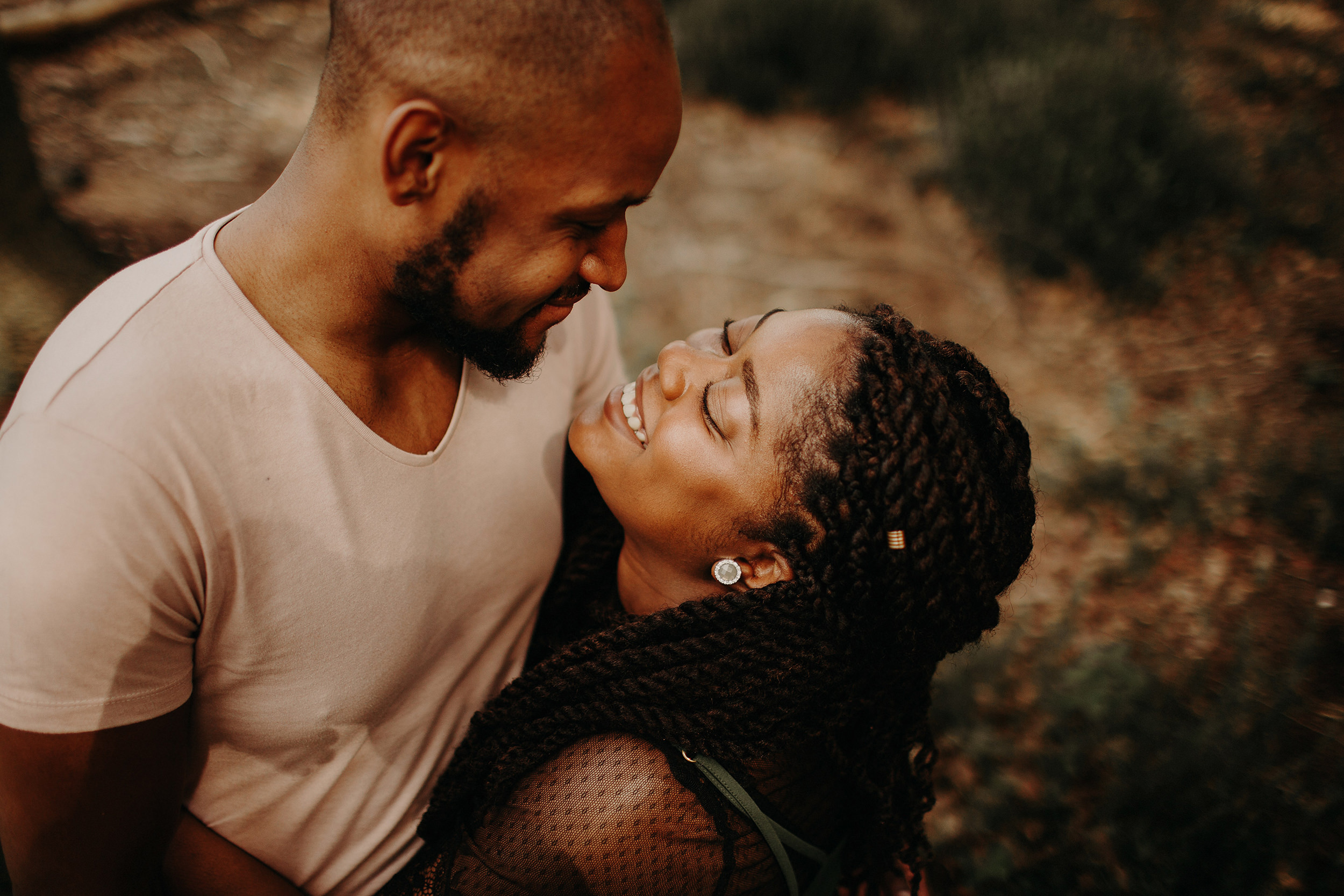 engaged couple share a laugh whilst holding each other in the black park