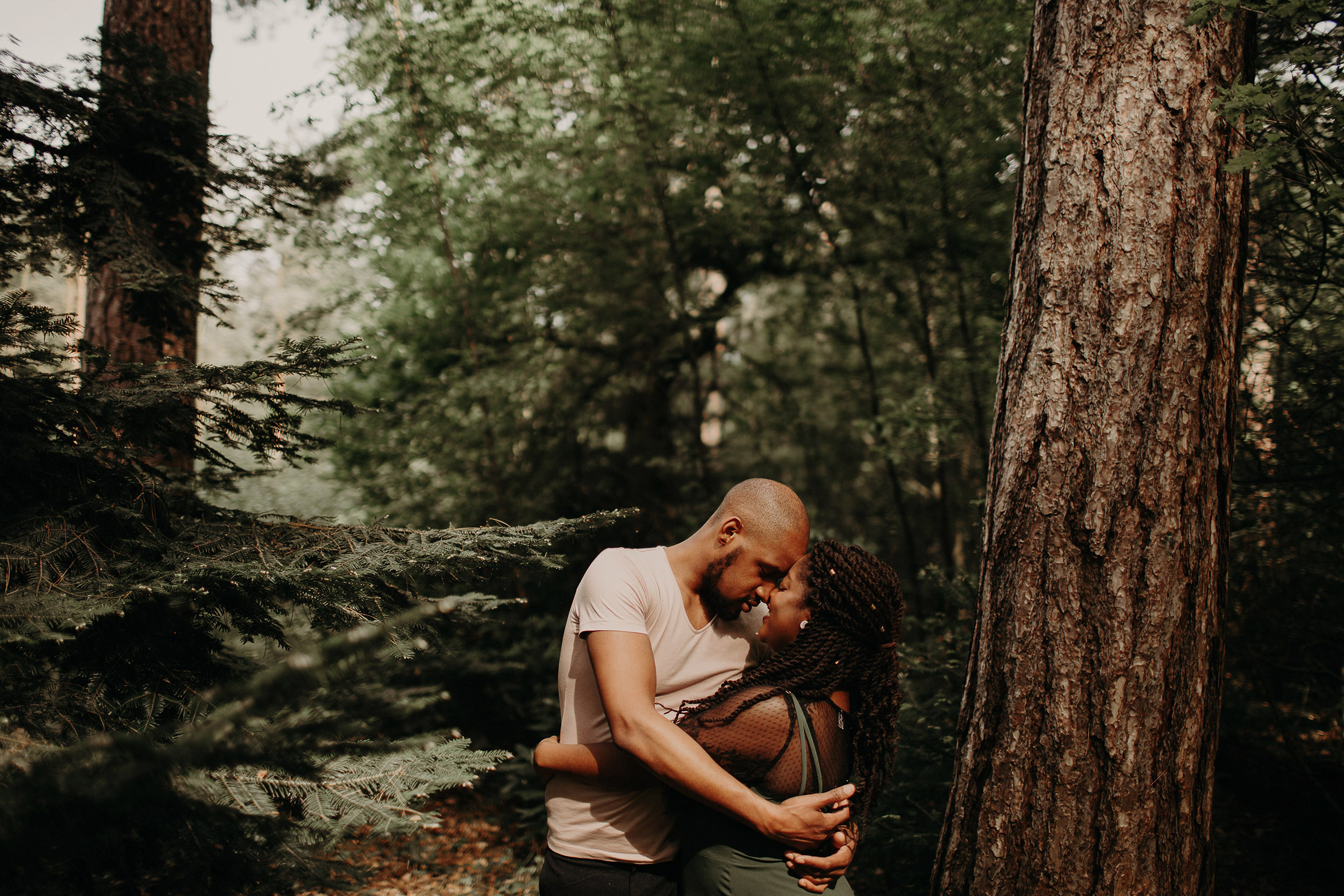 engaged couple touch foreheads whilst in the black park