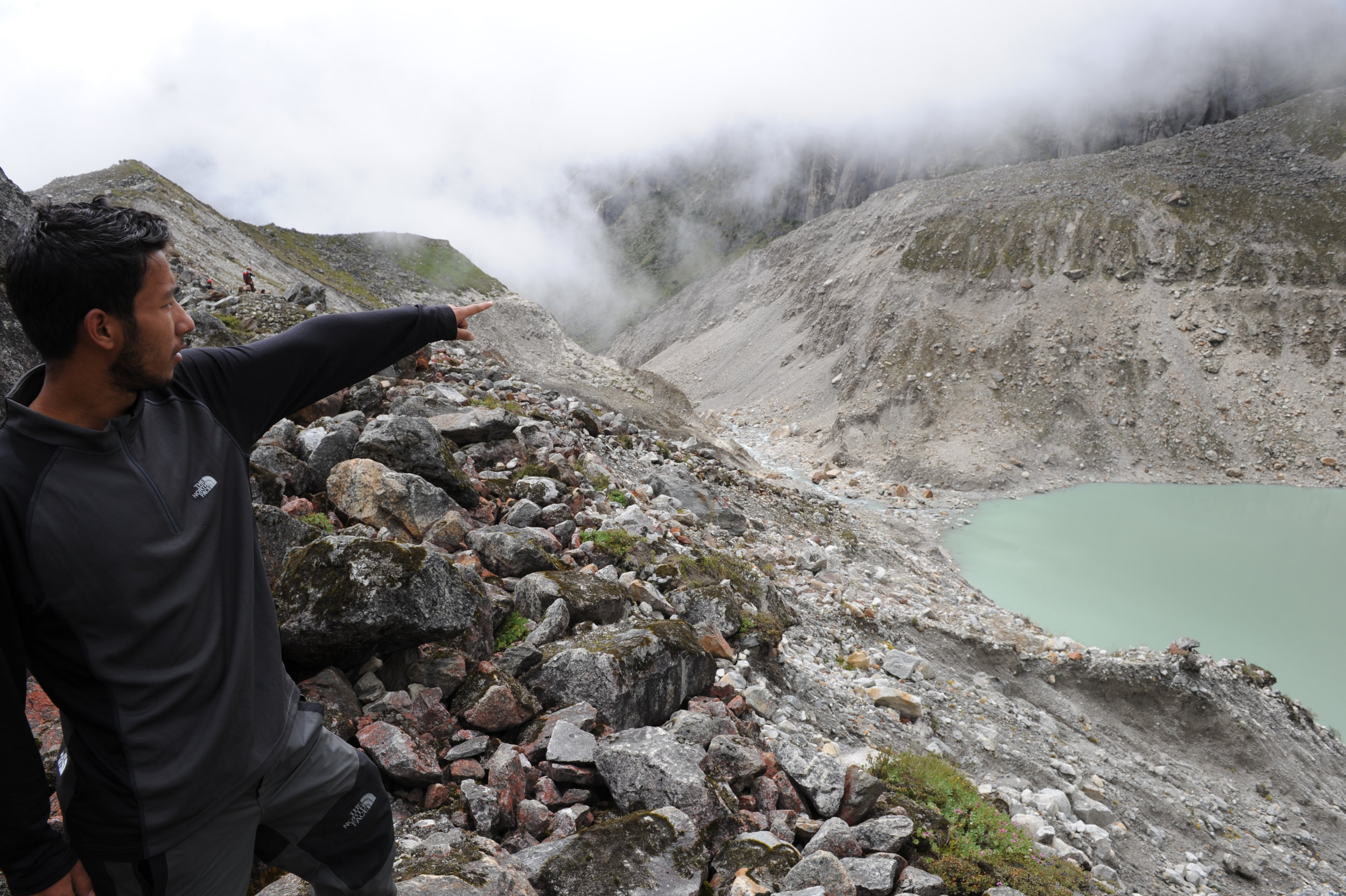 Samir shows the top of the 100m-high and 300m-wide moraine dam which collapsed in 1998.