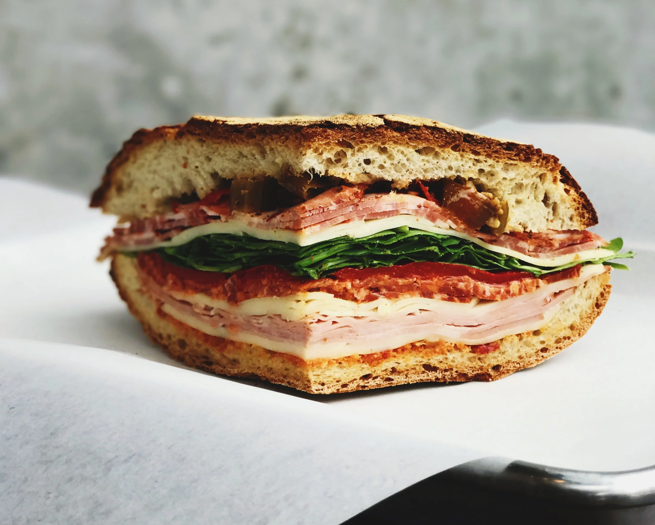 Capoccolla & Basil Capoccoll, house-made garlic aioli, basil, tomato, romaine, house-made pickles on brioche bun