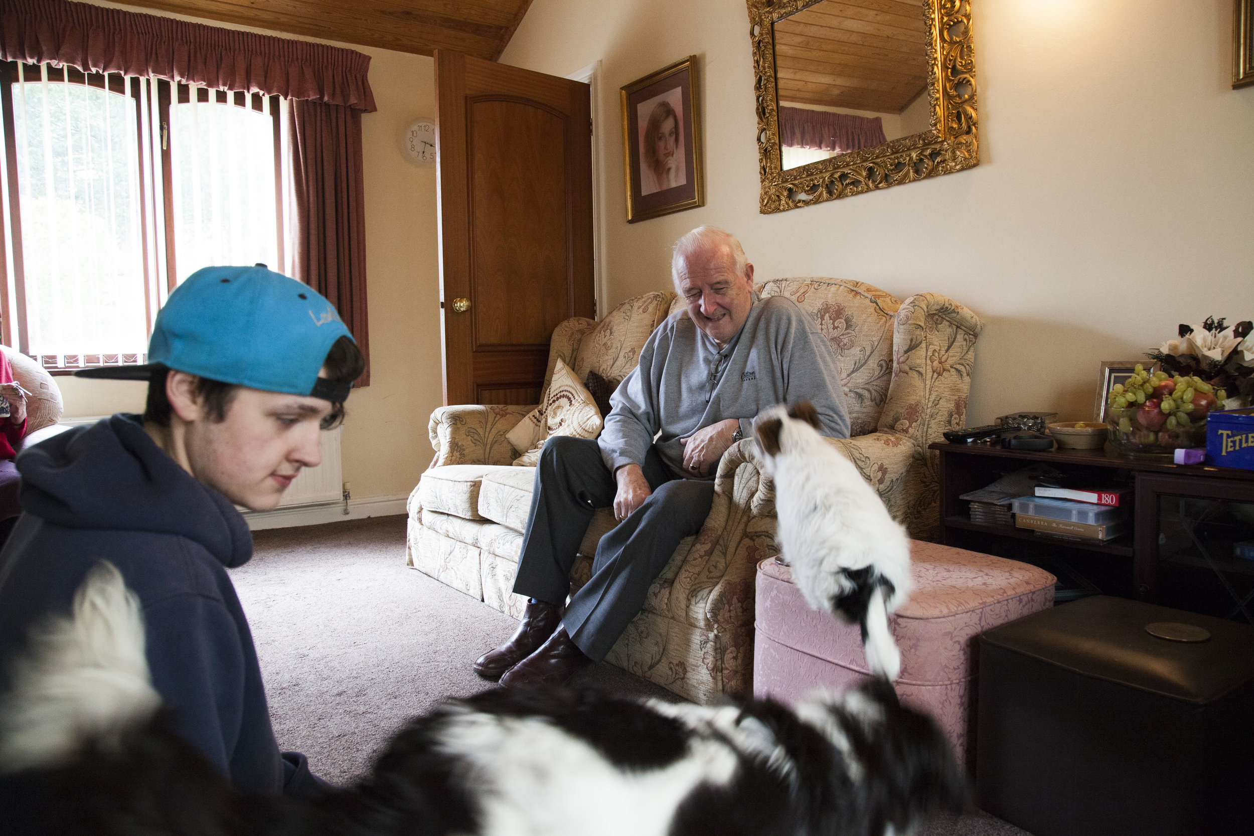 Graham and his grandson Luke playing with dogs in his living room. 