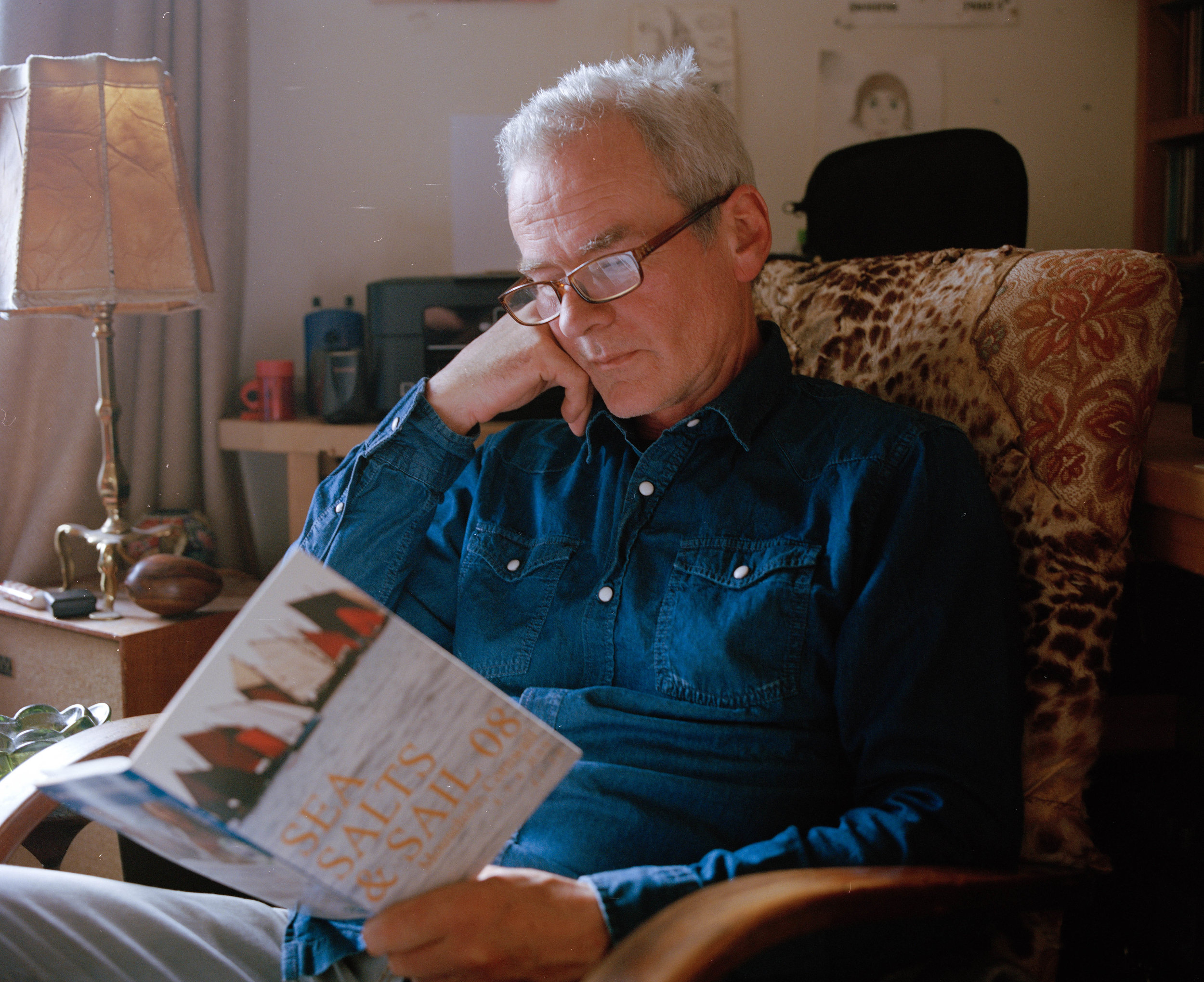 Neil reading a leaflet in his house. Neil says " I think that success is having a family around you, you don't need more than that really." 