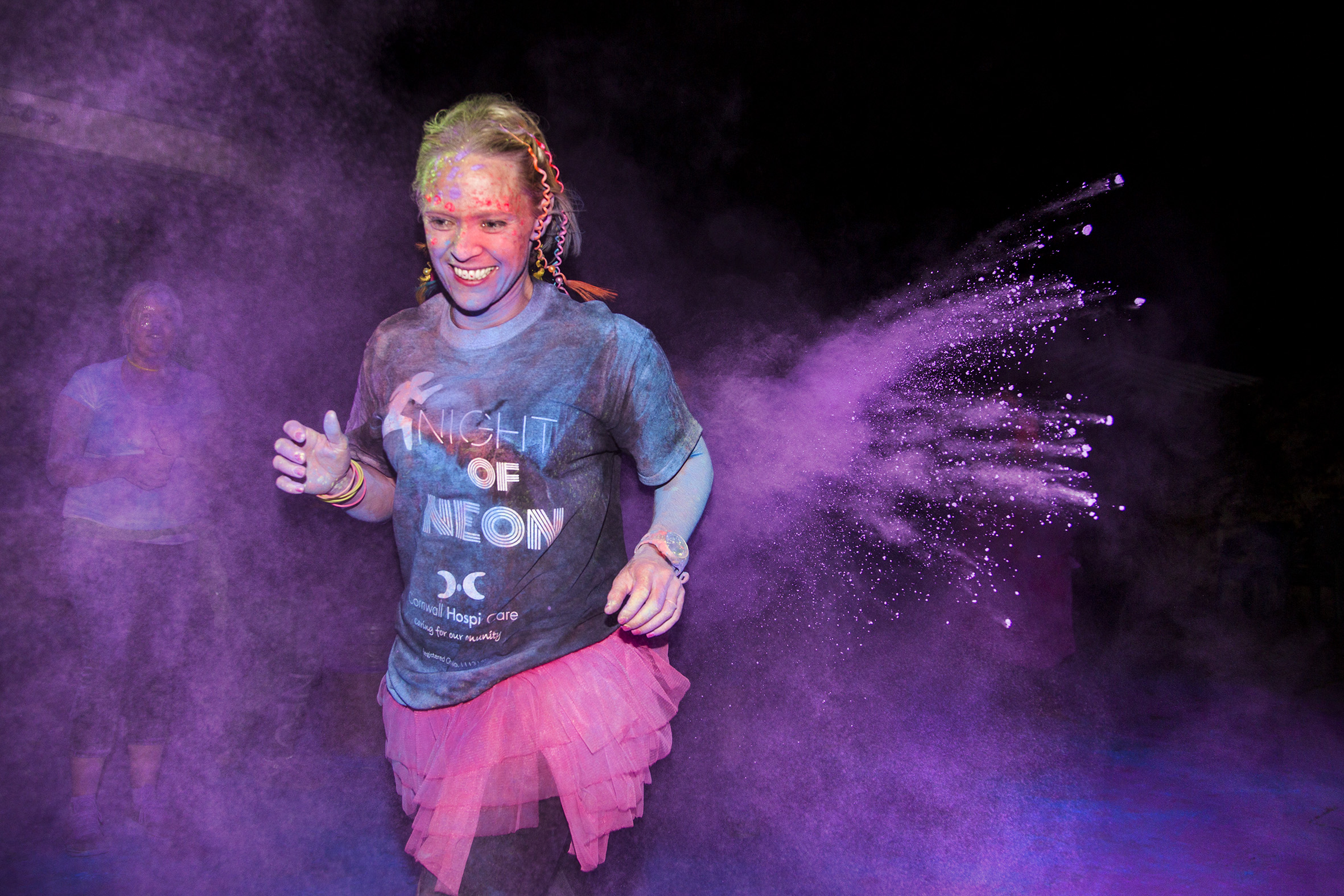 Night of neon charity runners. Participators running in the night of neon 10 mile charity race, dodging dry paint that is being thrown at them at set markers across the course. The race is a 10-mile run around Flambards theme park, participators have to dress in neon colours to raise money for Cornwall hospice. All of the money raised from this event will stay within the county and go towards providing specialist care to people with life limiting illnesses in Cornwall, funding the teams at Mount Edgcumbe Hospice in St Austell and St Julia's Hospice in Hayle. It costs £8.4 million a year to run Cornwall Hospice Care, but only 11% of this is funded by the health authority, well below the national funding average of 34%. Which is the lowest government funding of any adult hospice in the country. It means Cornwall Hospice Care has to raise 89% of its funds from voluntary sources. Flambards, Helston, Cornwall, GB, 8/10/16