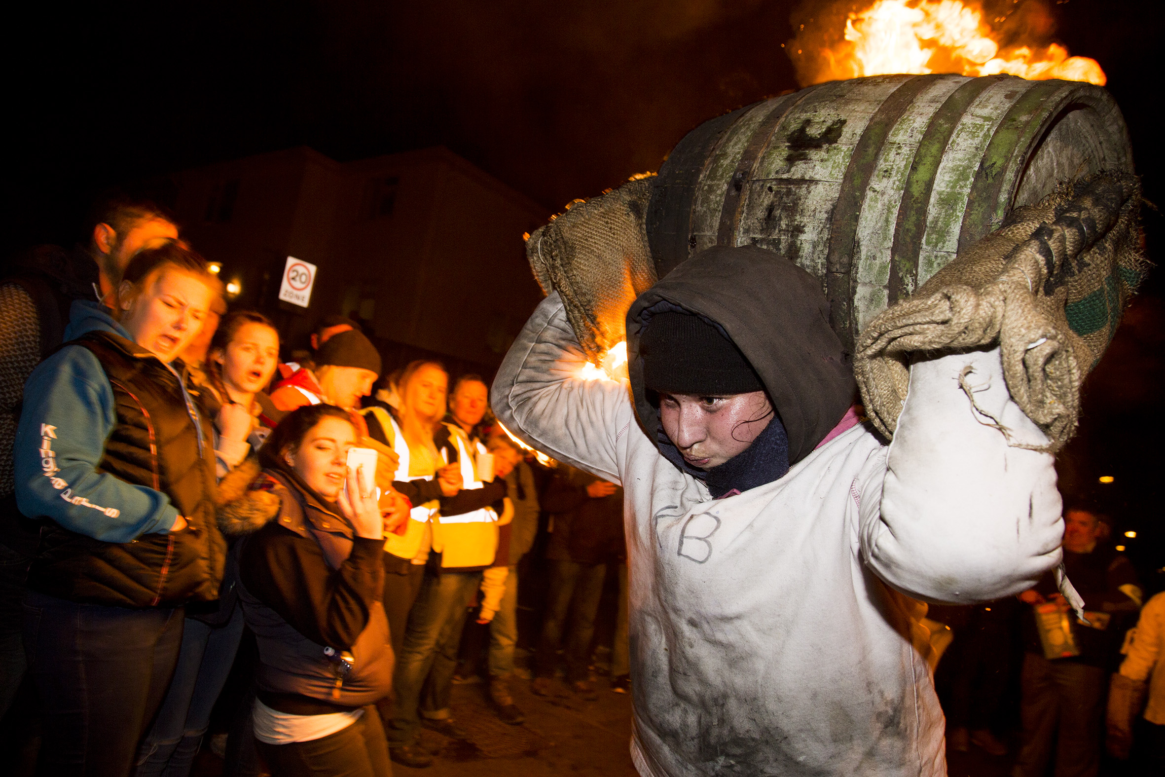 A teenage girl carries a flaming tar barrel through Mary's St.Ottery on Guy Forks night 2016. Ottery St. Mary is internationally renowned for its Tar Barrels, an old custom said to have originated in the 17th century, and which is held on November 5th each year. Each of Ottery's central public houses sponsors a single barrel. In the weeks prior to the day of the event, November 5th, the barrels are soaked with tar. The barrels are lit outside each of the pubs in turn and once the flames begin to pour out, they are hoisted up onto local people's backs and shoulders. 
