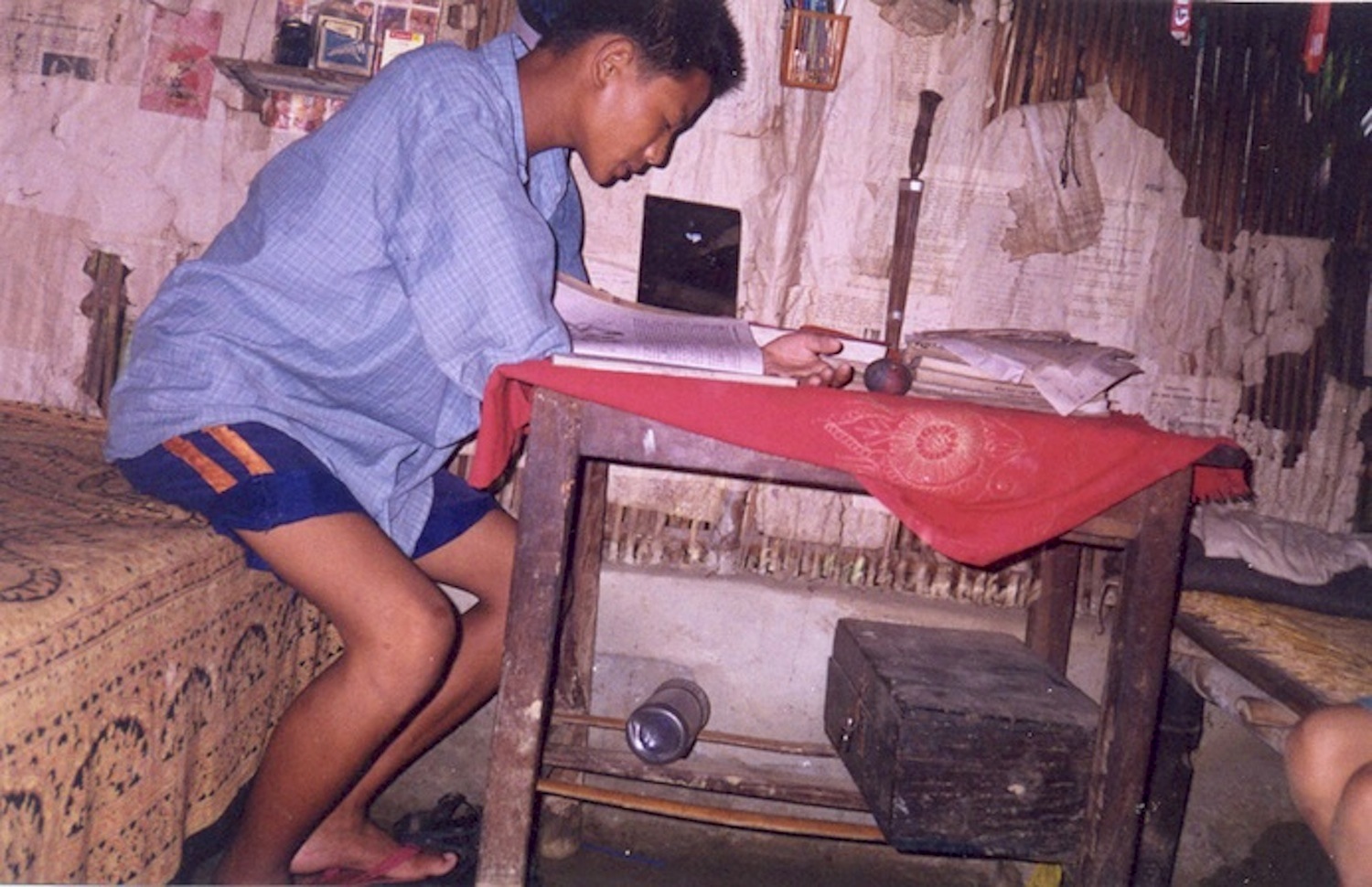 He is my brother. He is studying in Class VIII. He wakes up early in the morning because his examination is coming very near. He sits on the bed and keeping his books on the table, he starts reading. He is naked because he has just woken up, lit the lantern and started studying. (c) Yamuna / Rose Class / PhotoVoice