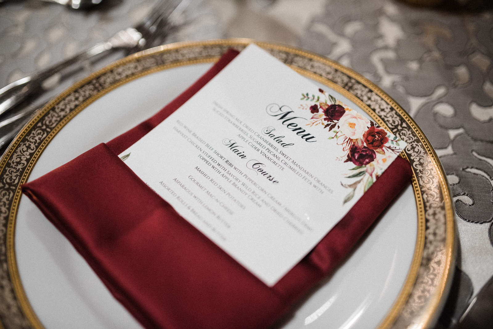  Place setting with burgundy napkin and floral theme menu card at Americas Packard Museum wedding 