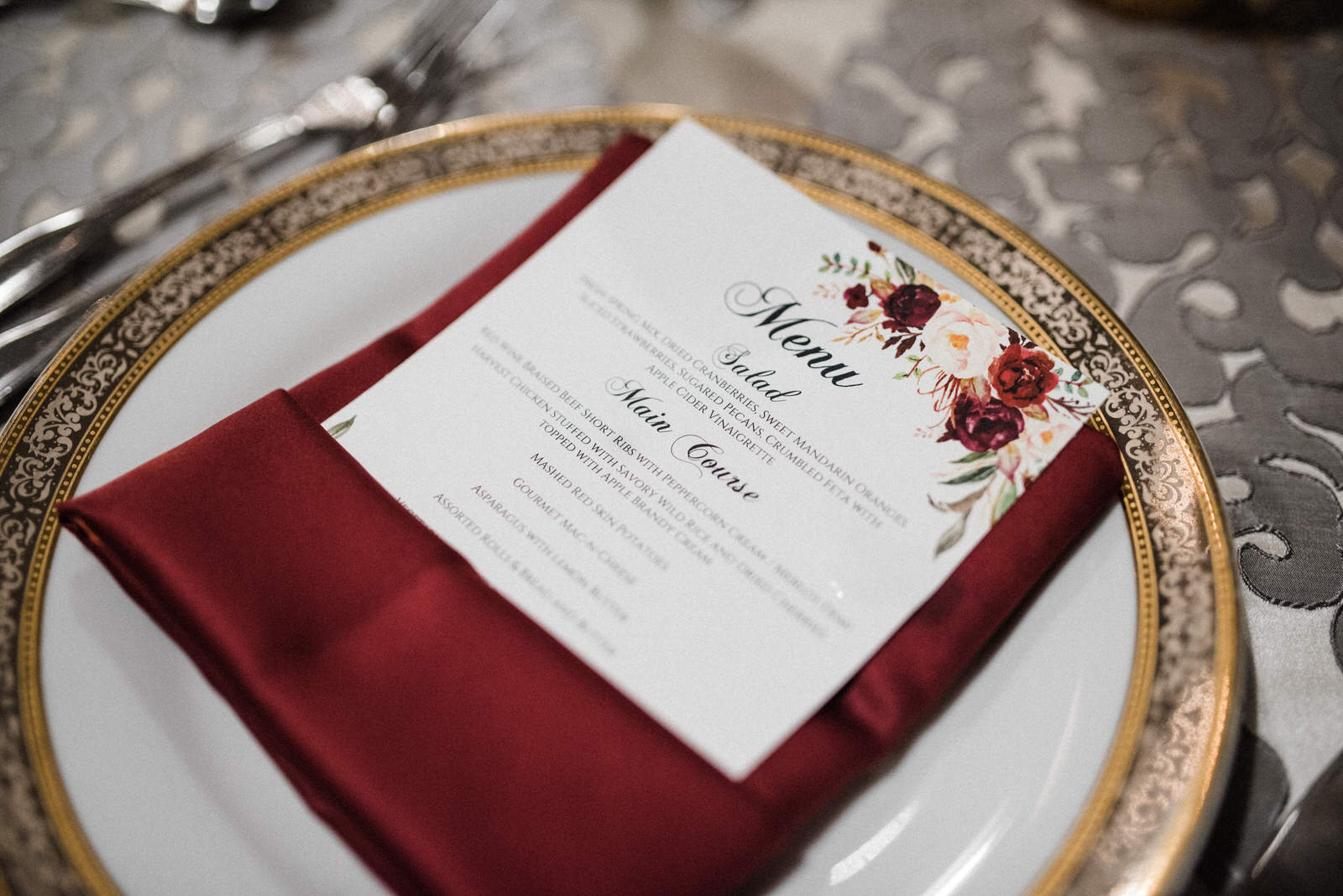 Place setting with burgundy napkin and floral theme menu card at Americas Packard Museum wedding