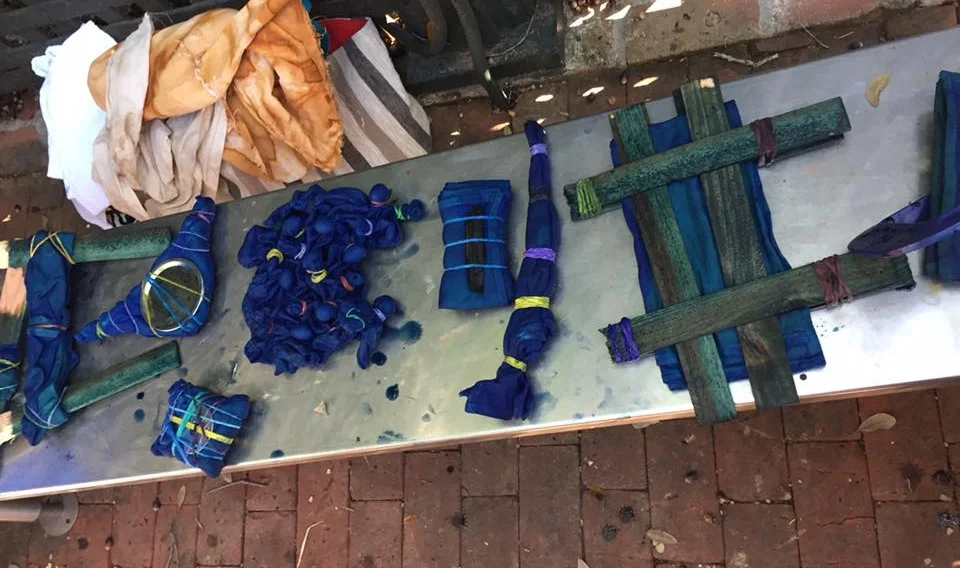 Several different resists being tried out. Students used wood shims, lids from jars, rubber bands, clothes pins, and other items to block the dye and make patterns on their napkins. 