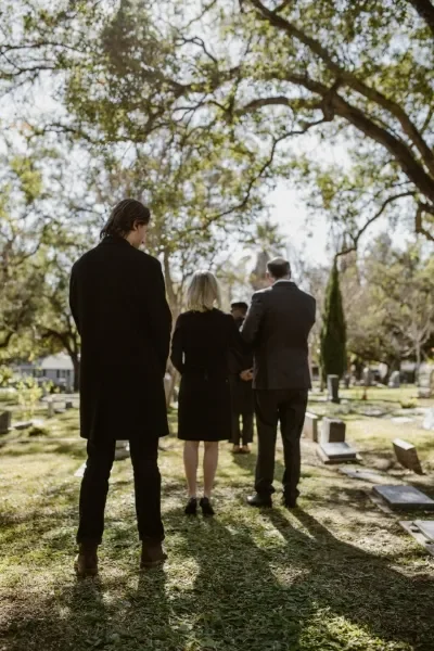 Group of people standing apart at a cemetery facing away