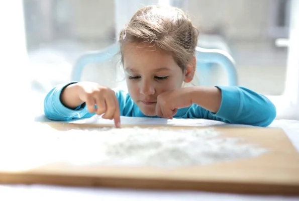Girl playing with flour on a cutting board