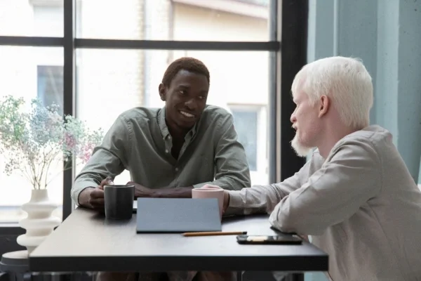 You man talking with older man at a table smiling