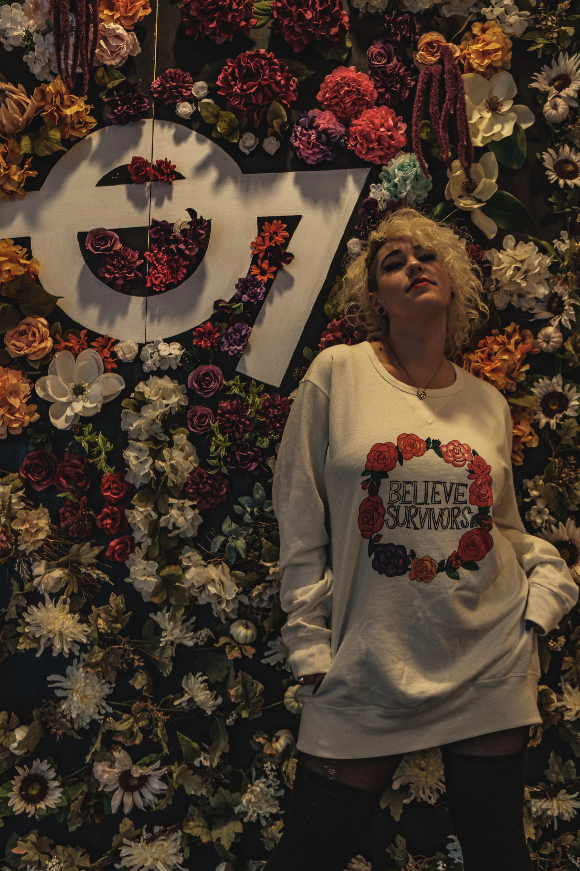 white unisex sweatshirt screen-printed with "believe survivors" text in ring of flowers graphic - dfrntpigeon