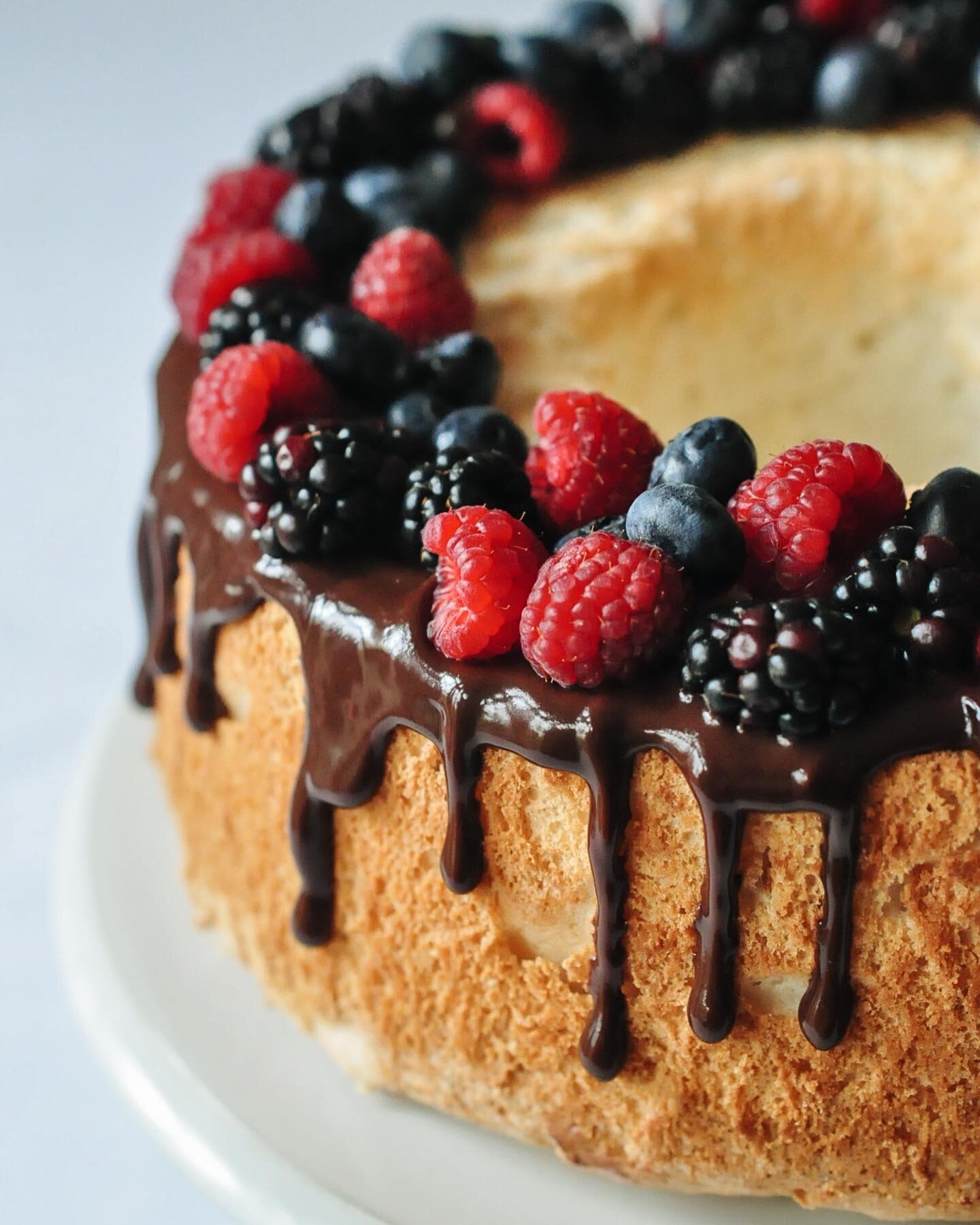 Angel food cake with a dark chocolate ganache drip and fresh mixed berries is heavenly 🤤 and perfect for your angel mom on Mother's Day! Order yours at the link in our bio!