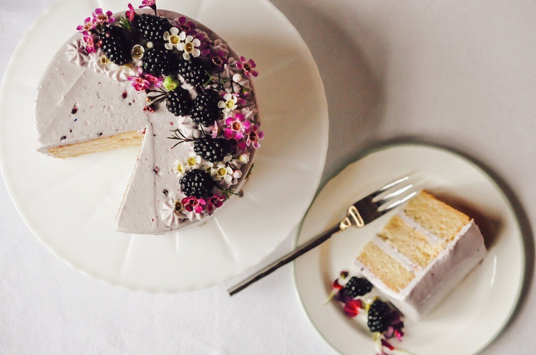 Our Almond Blackberry Cake is such a cutie with its little flower crown, don't you think?! It's light and buttery almond cake layers with blackberry icing made with our scratch-made blackberry jam, topped with fresh blackberries and lovely flower acc